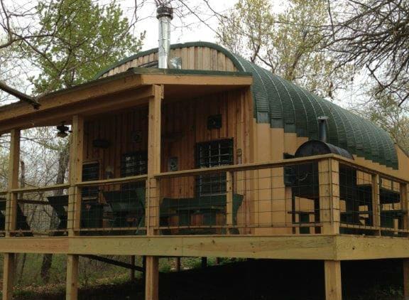 cabin on wood pier foundation with green and tan painted arches, custom wood endwall