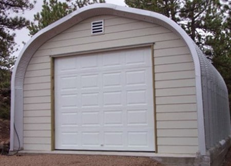 a-model quonset hut with tan vinyl siding and white garage door