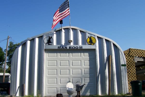steel a-model quonset hut with white garage door and the words "man room" on the endwall