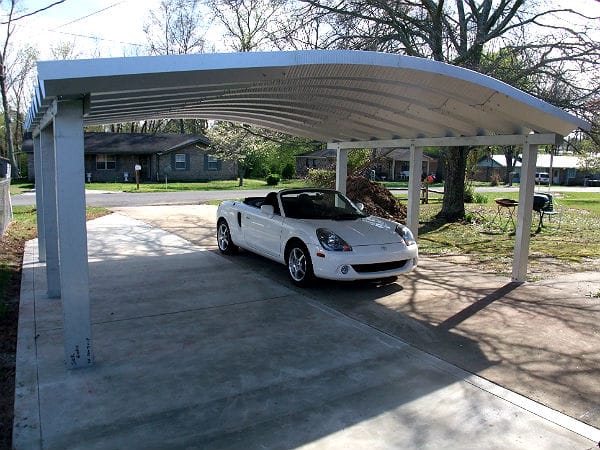 wide steel arch carport with white convertible underneath