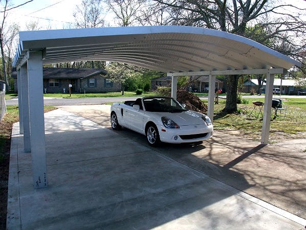 wide steel arch carport with white convertible underneath