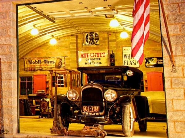 inside steel quonset hut building with vintage car and vintage workshop signs