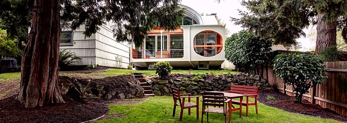 mid century modern style house with steel arch in background of backyard