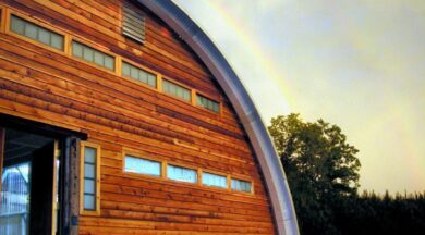 steel quonset hut q-model with wood endwall and rainbow in background