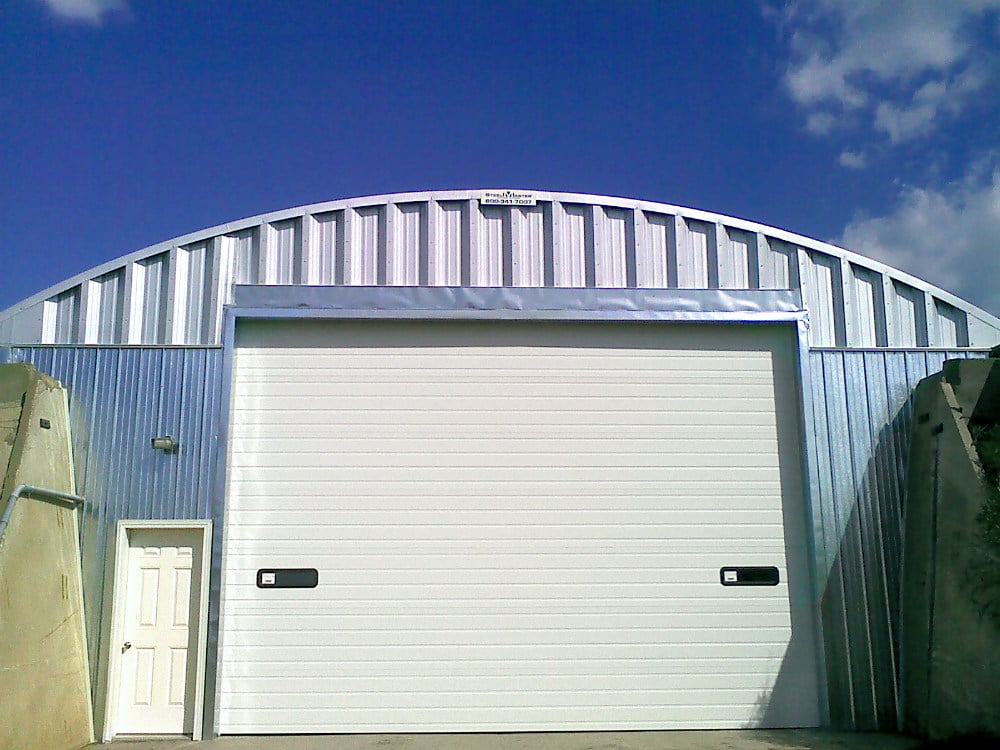 large custom steel building with white garage door and concrete walls