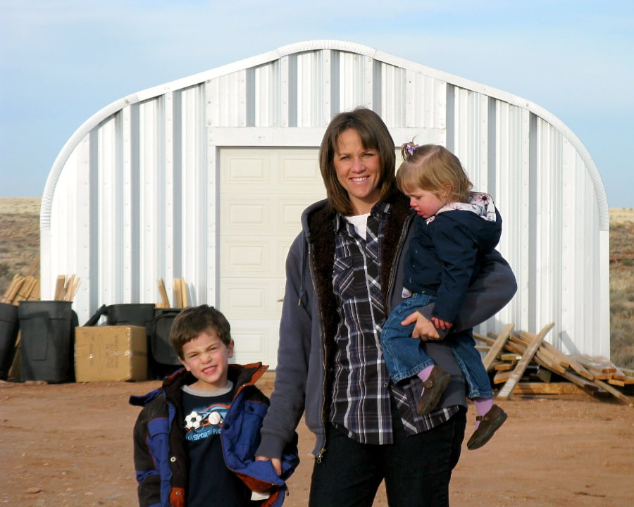 mother with two children and steel quonset hut in background