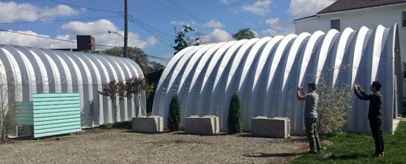 two men taking pictures of steel quonset huts in detroit