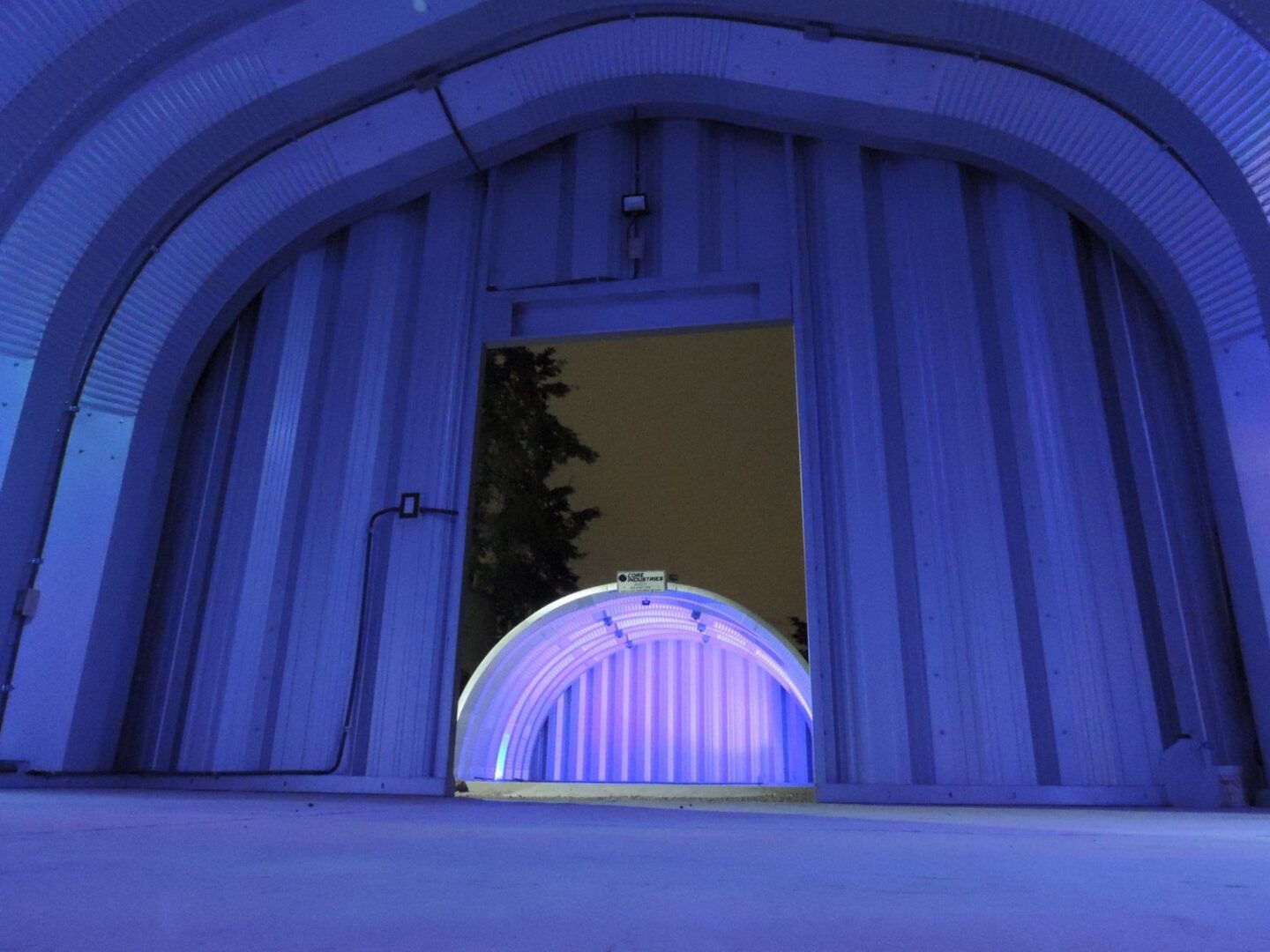 steel quonset hut illuminated with purple lighting