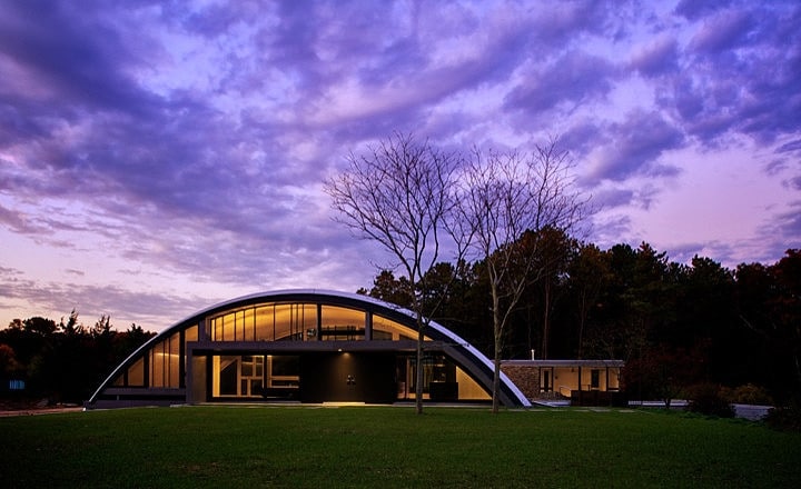 home with quonset hut arch during the evening with purple sunset