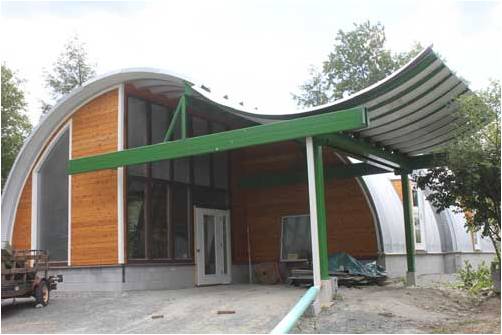quonset hut building with wooden endwall and upside down arch awning with green accents