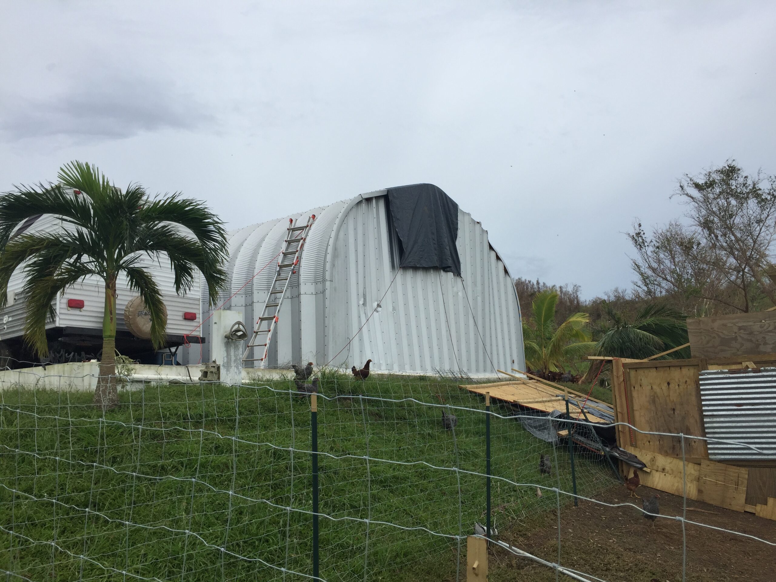 steel quonset hut with minor dent in rear endwall partially covered by tarp