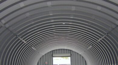 inside of steel quonset hut with front endwall and open garage door in distance