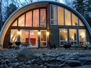 Exterior view of Quonset Hut home with windows at front of house.