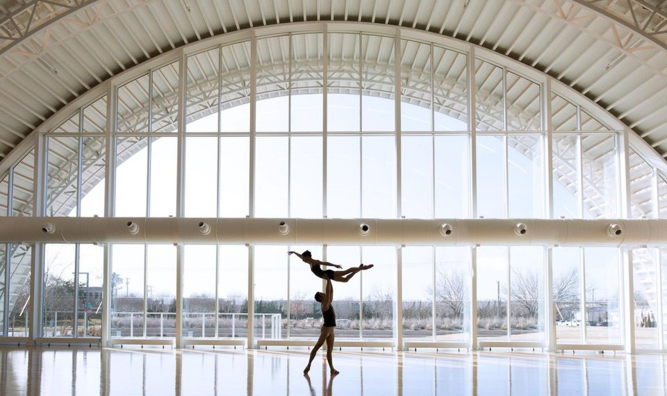 Male ballet dancer lifts ballerina in the air at quonset hut ballet studio