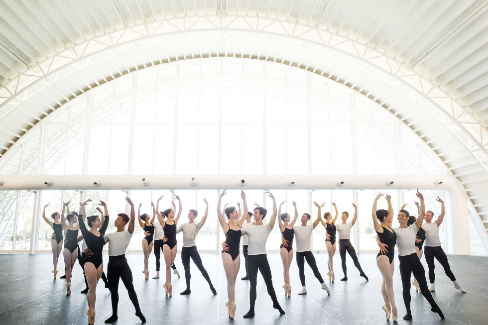 Male and female classical ballet dancers perform in large quonset hut ballet studio