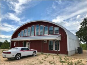 Red SteelMaster Metal Quonset Hut home with car in front