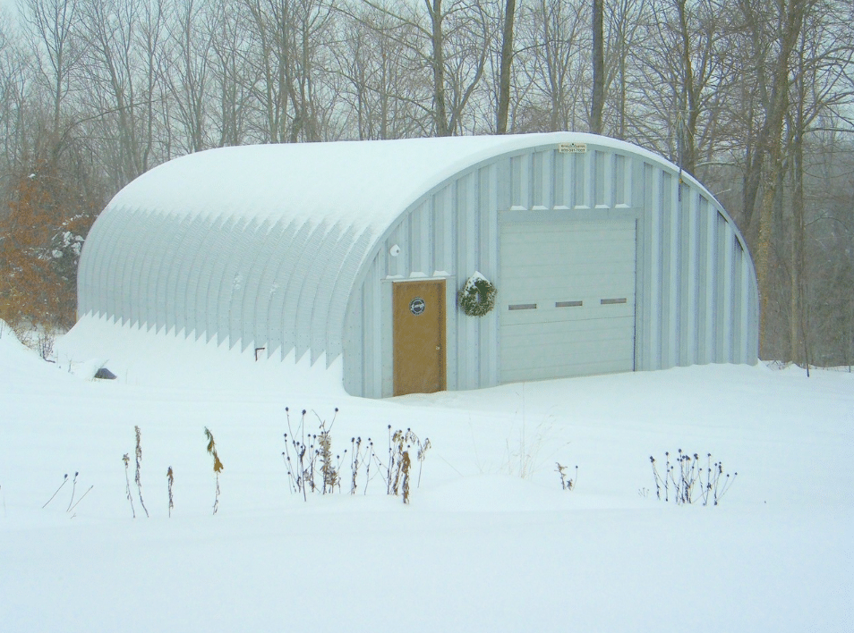steel quonset hut with wreath near door with snow on top and on the ground