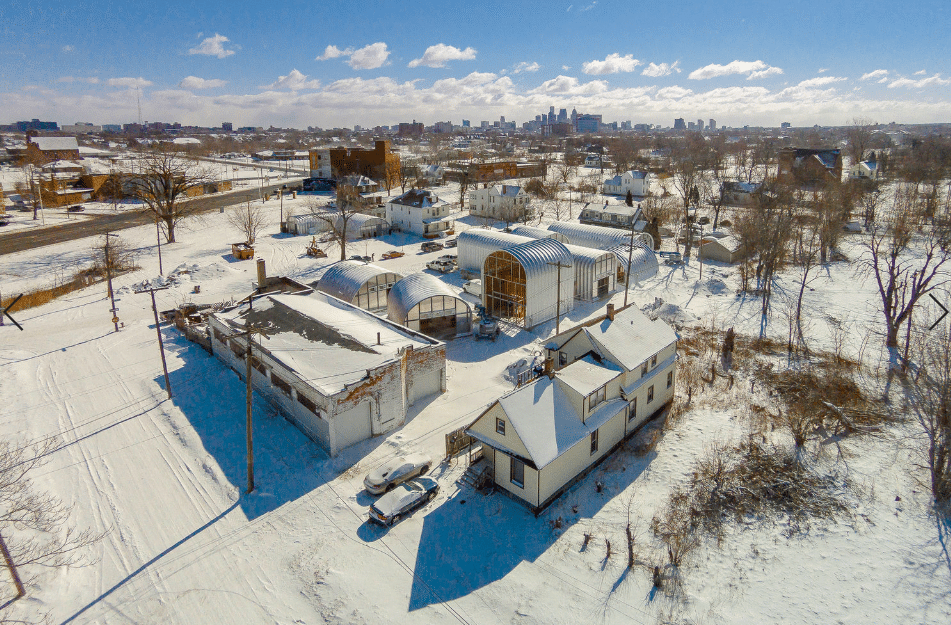 aerial image of quonset hut village with ground and buildings covered in snow