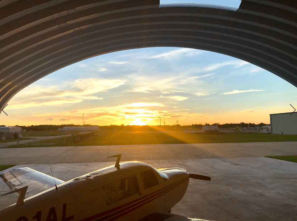 quonset hut hangar with plane inside overlooking sunset