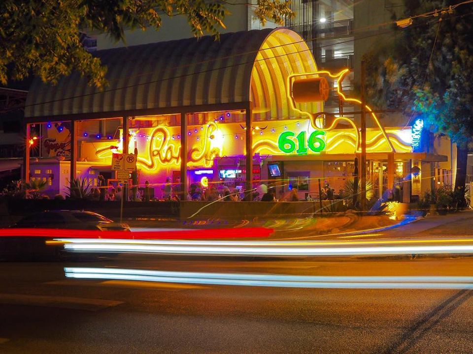 outdoor patio eating area covered by large steel canopy at night with neon lighting