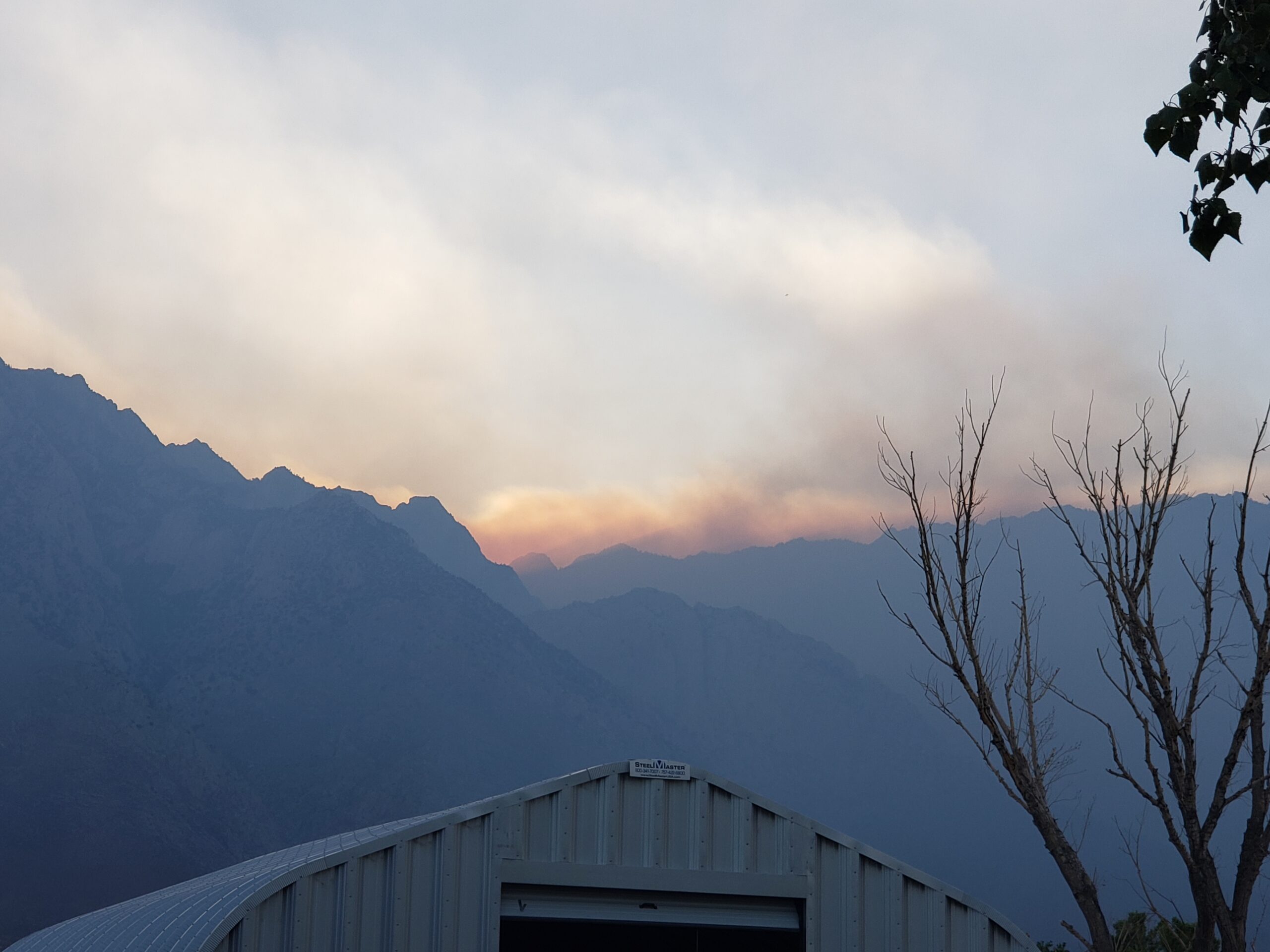 cut off photo of quonset hut with sunset and mountains in background