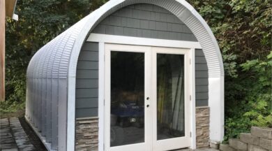 small s-model quonset hut in backyard with wood shingle and stone siding, french doors and atv inside
