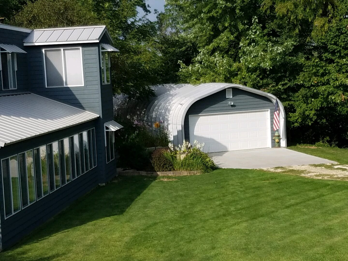 quonset hut with gray siding and large white garage door with American flag