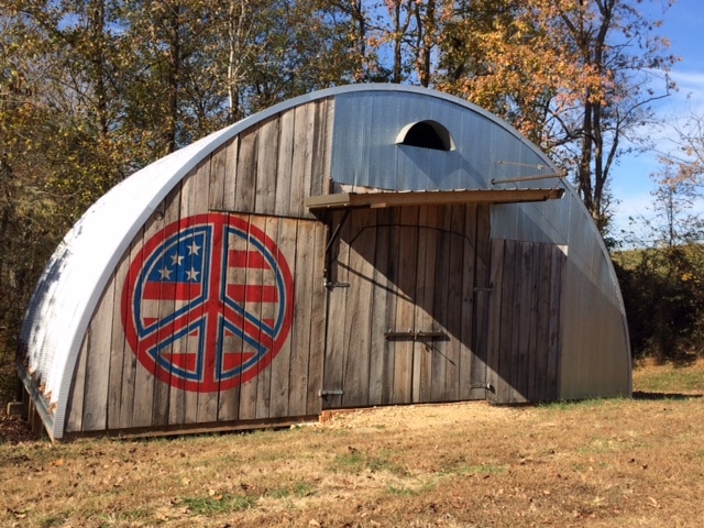 q-model quonset hut with wooden endwall with painted peace sign with american flag