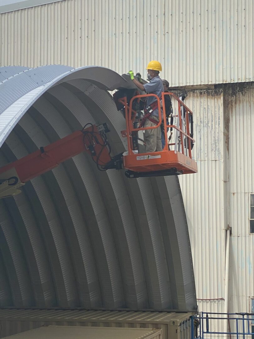 Men on orange crane putting together steel arches