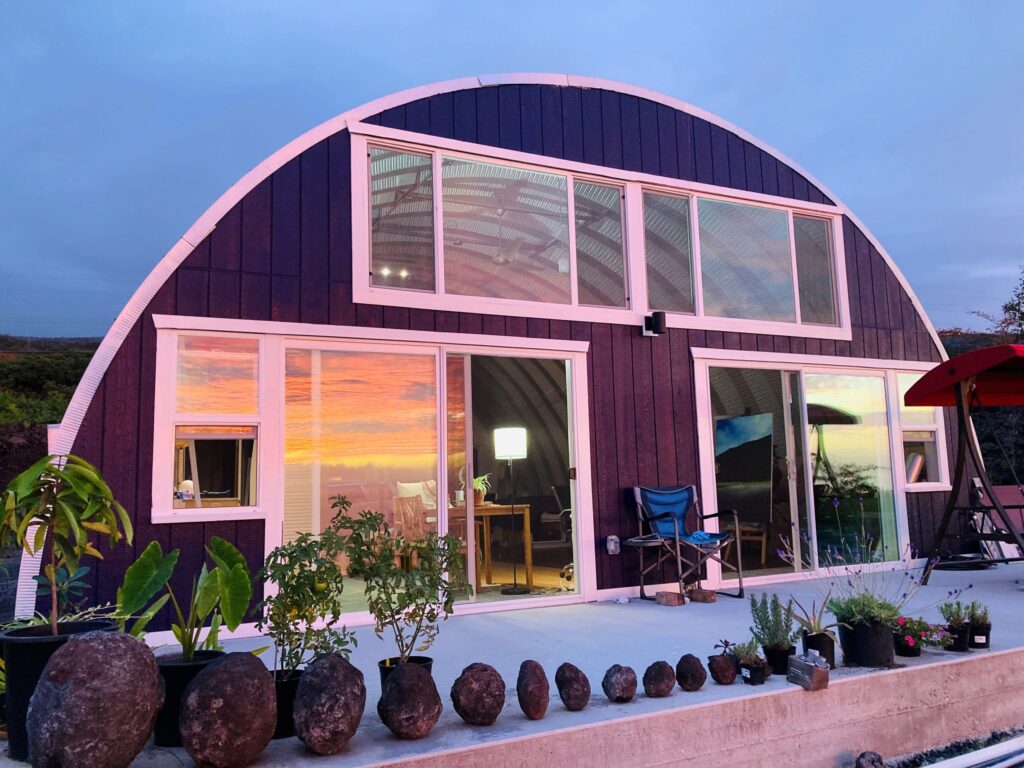 Quonset hut home with custom endwall full of windows and 2 sliding glass doors on concrete foundation