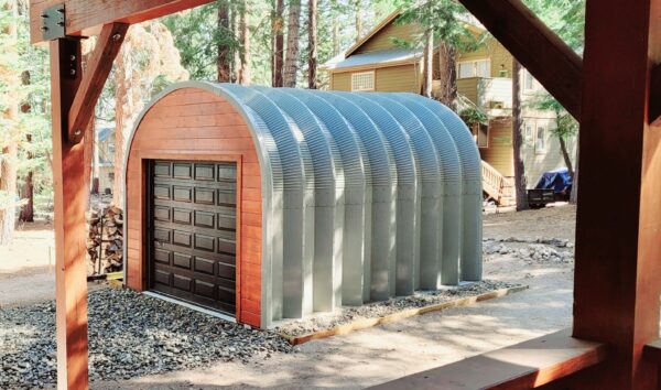 Quonset shed with custom brown endwall, dark brown garage door, pine tree forest