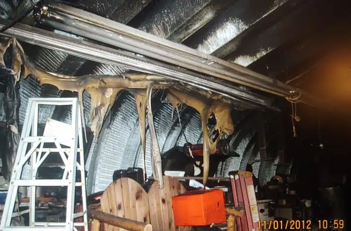 Inside Quonset workshop: burnt and melted objects, steel arches blackened but not damaged.