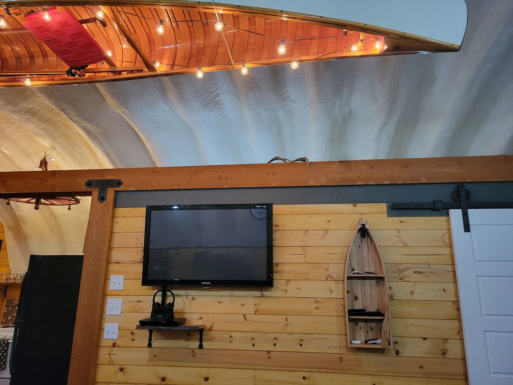 Inside of quonset home, canoe with lights hanging upside down from ceiling