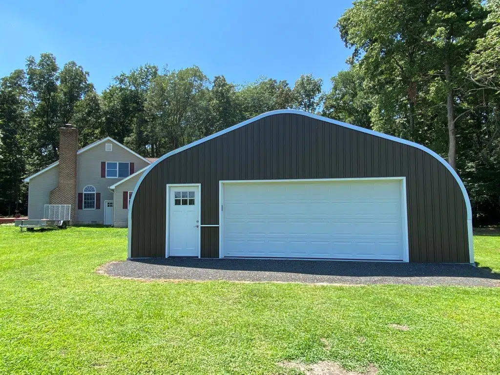 A-model Quonset garage with custom endwall, white door, white garage door, home and trees in background