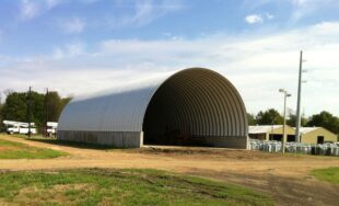 large steel arch structure mounted on concrete stem wall