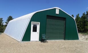 Steel Quonset workshop with dark green front end wall, white entry door, and green garage door