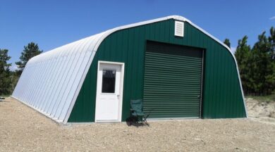 Steel Quonset workshop with dark green front end wall, white entry door, and green garage door