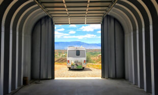 inside of quonset hut with garage door open and view of RV with mountains and blue sky in background