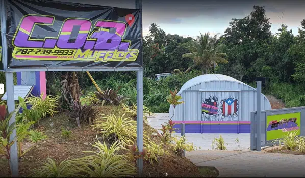 Personalized Quonset auto shop in Puerto Rico, steel endwall, painted front, purple, pink, and green striped base.