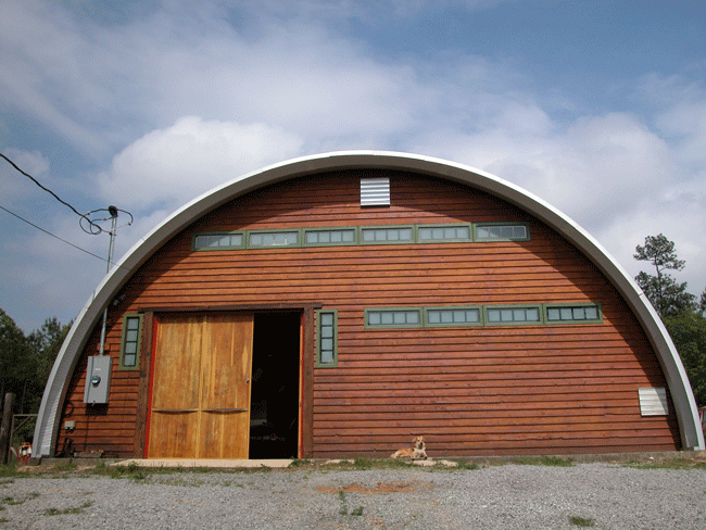 Q-Model workshop with custom recessed front end wall, sliding wooden door, and a dog laying in front