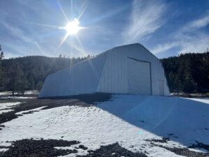 X-Model Quonset hut with sun glare and tree background.