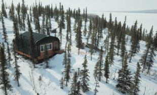 Painted A-model Quonset cabin in the snow covered Alaskan wilderness.