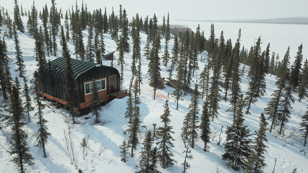 Painted A-model Quonset cabin in the snow covered Alaskan wilderness.