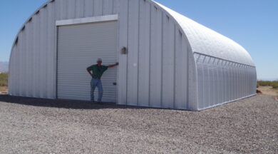 S-Model Quonset hut with steel end wall, garage door, and man with a green shirt and hat leaning against the front.