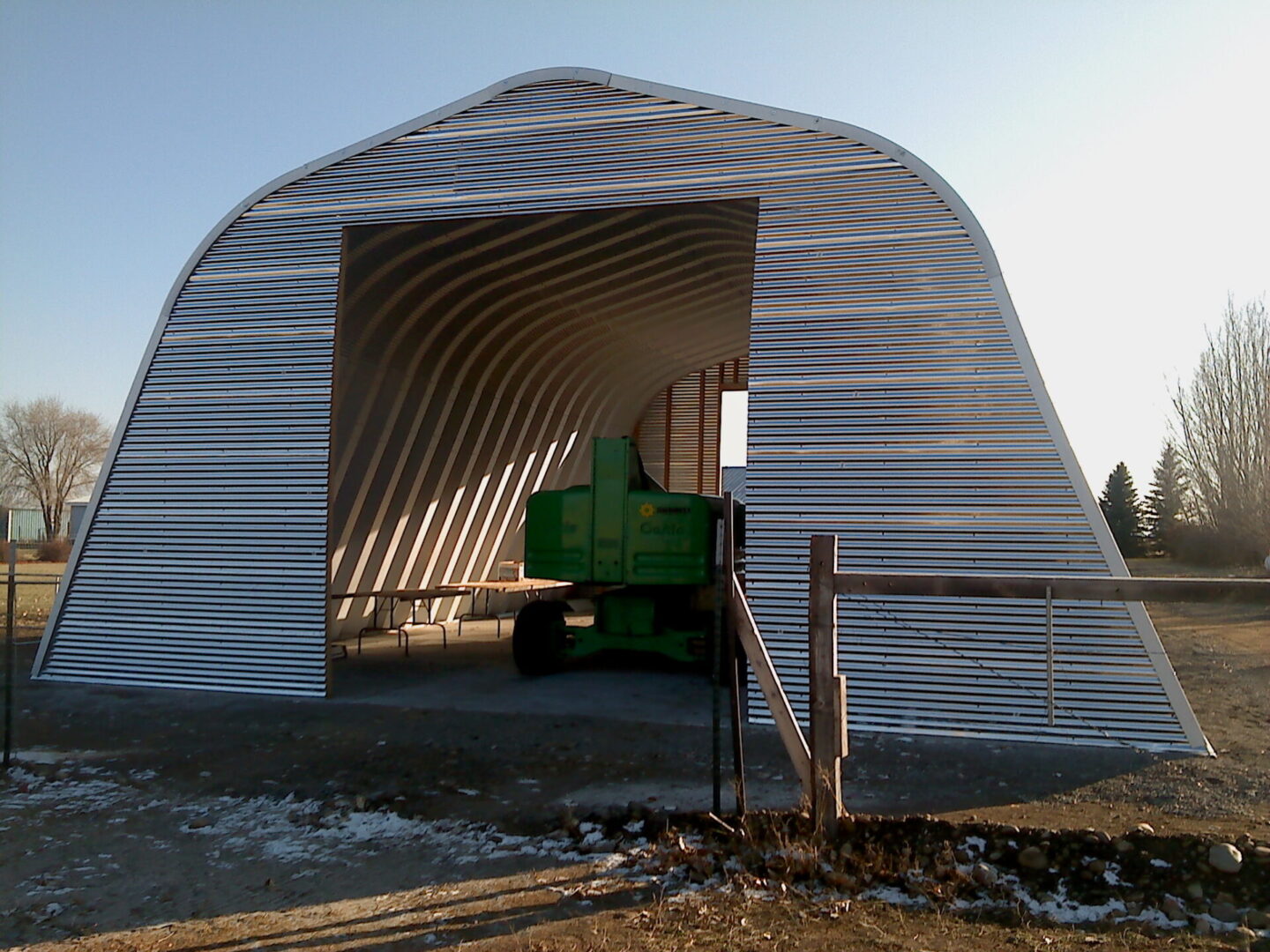 X-Model Quonset hut with green farm equipment inside