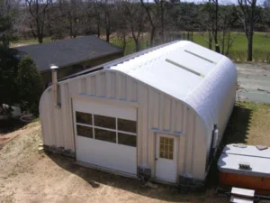 steel garage with white garage door, skylights and stove pipe sticking out of endwall