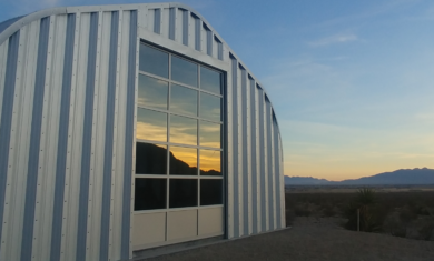 a-model steel quonset building, glass door reflecting sunrise