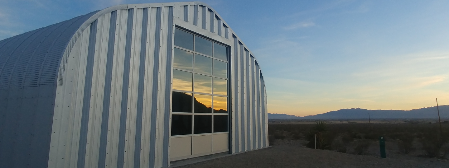 a-model steel quonset building, glass door reflecting sunrise