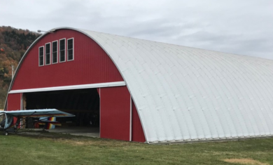 Front and sideview of large q-model airplane hangar with custom red endwall, small plane in front