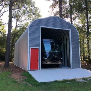 tall steel building with gray vinyl siding, garage door open with RV inside